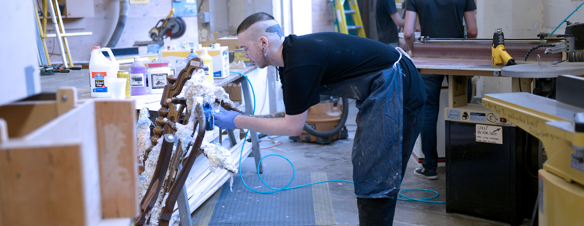 Art Student with apron and gloves in workshop doing detailed woodwork