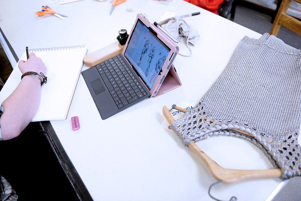 Cornish Costume Design student working with garment, sketch pad, and labtop