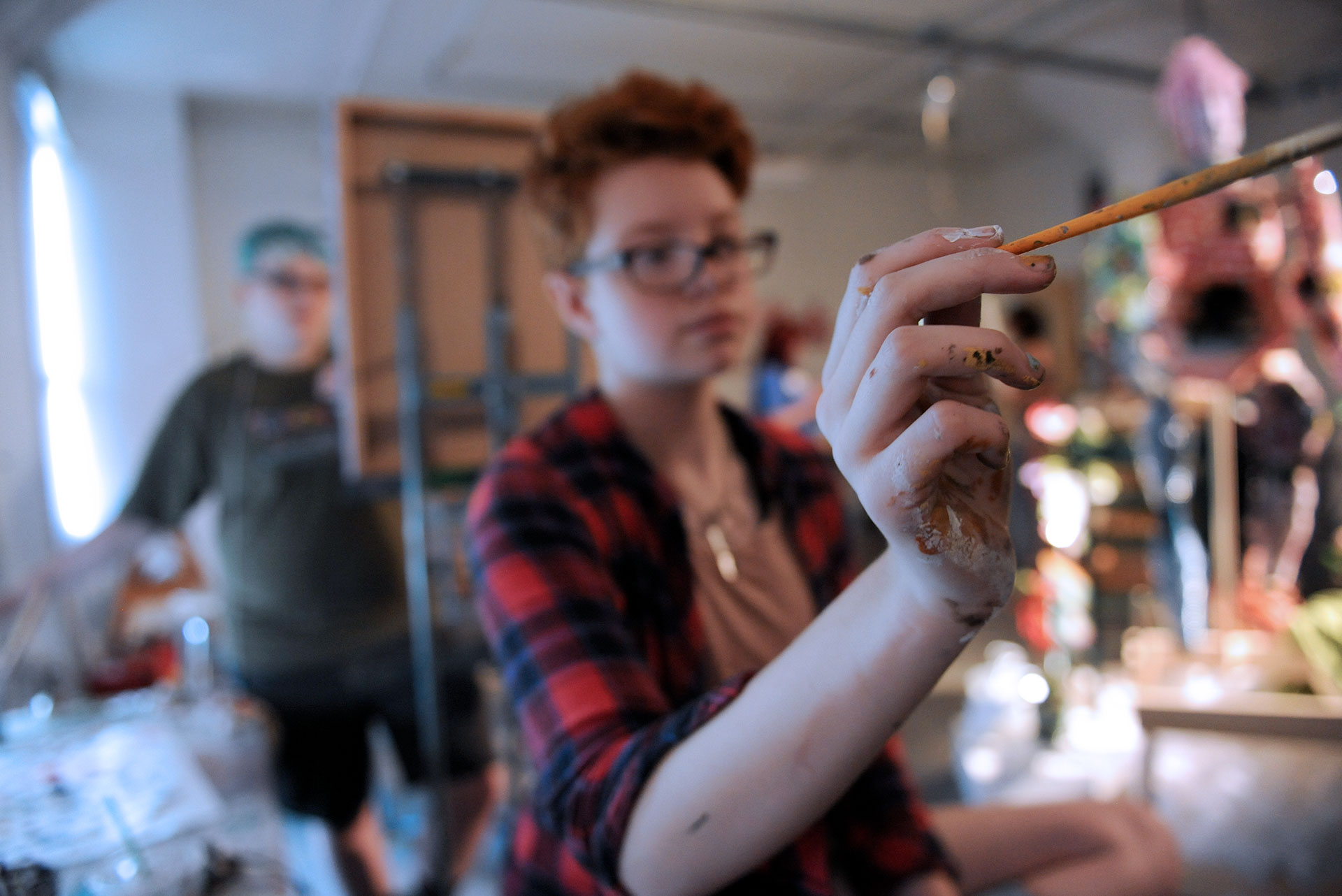 Art Student Painting with out of focus student behind them standing at an easel