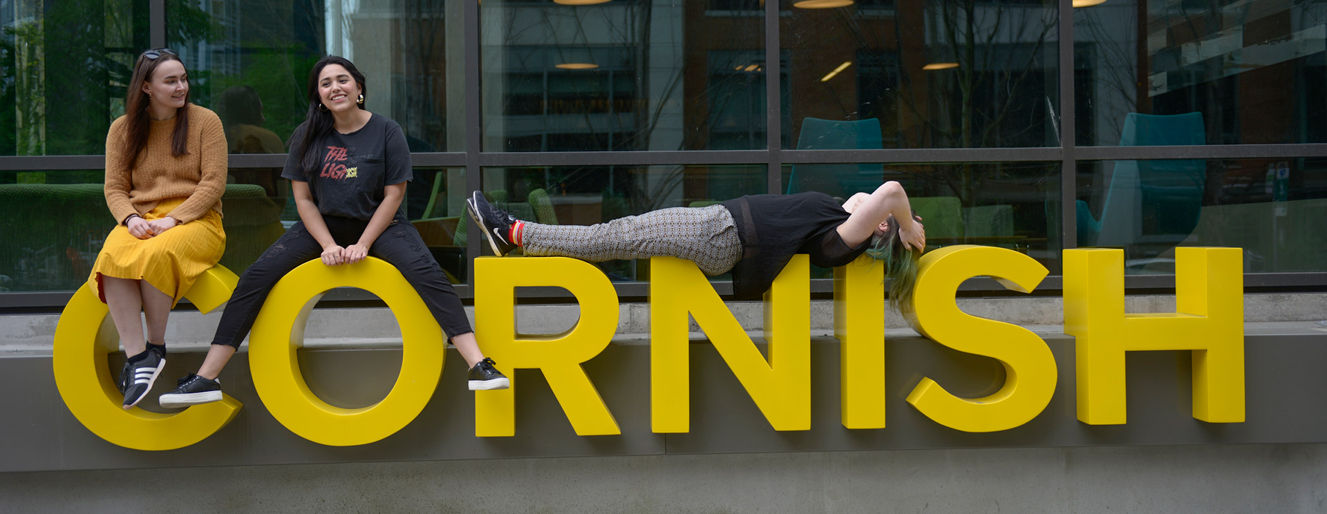 Students sitting on the large Cornish letters posted outside the Commons residency building