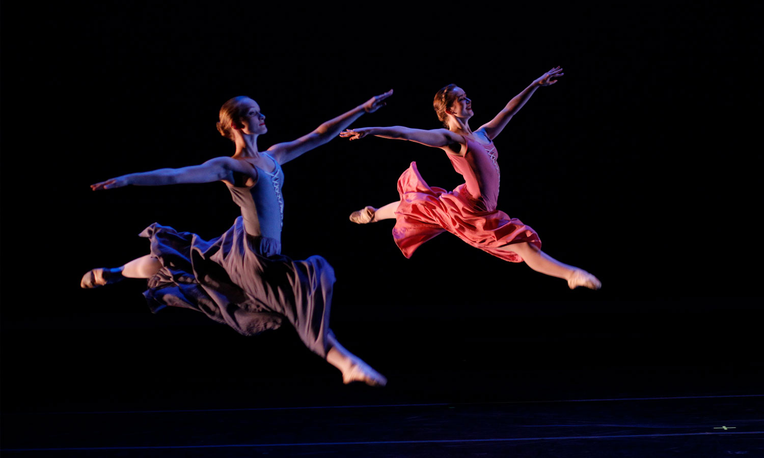 Two dancers mid-jump