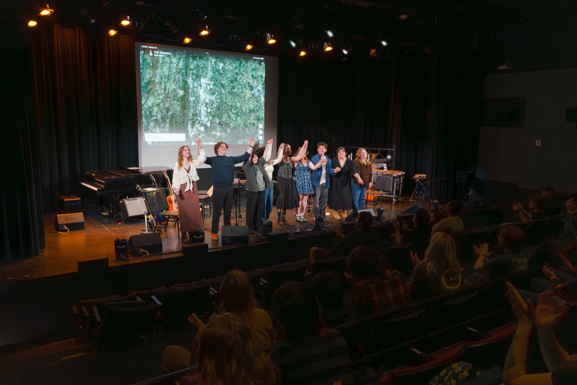 Students take a bow on stage at the Raisbeck Auditorium