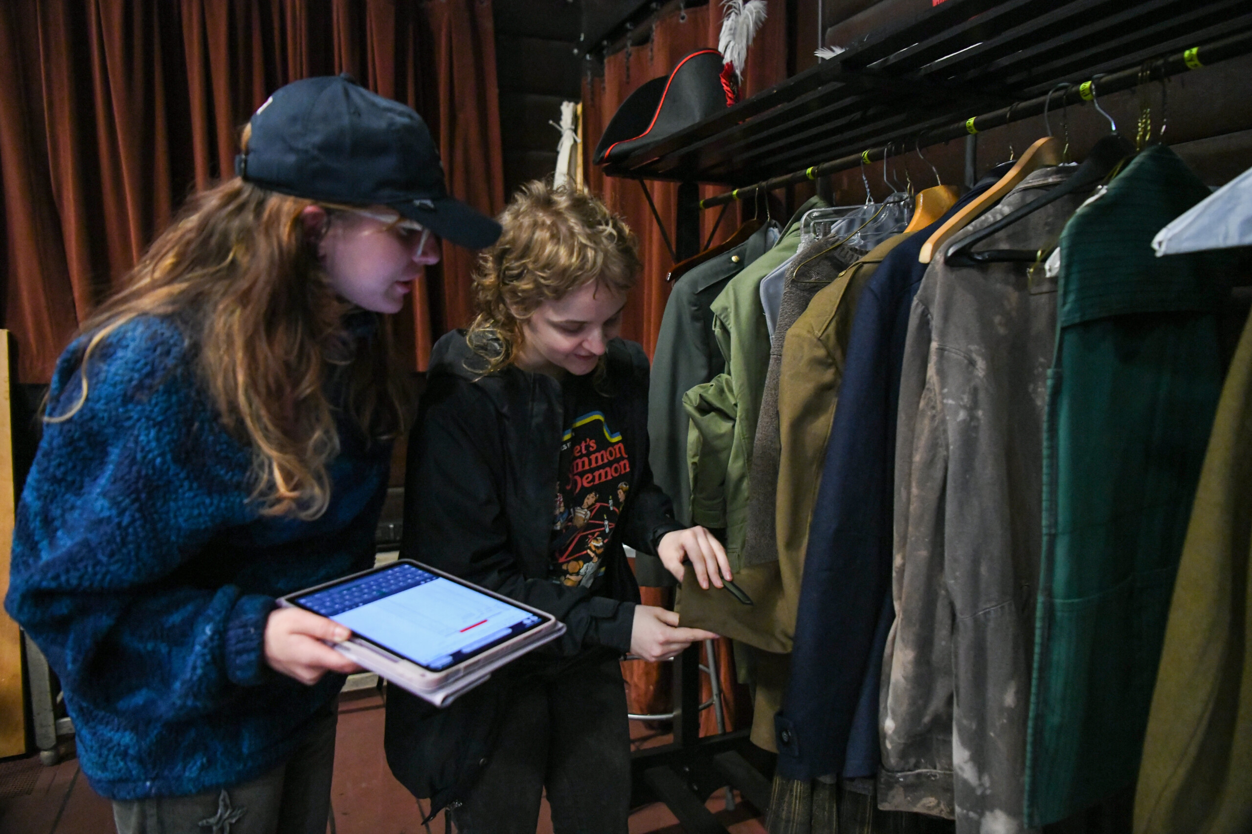 two back of house crew members inspect theatre costumes