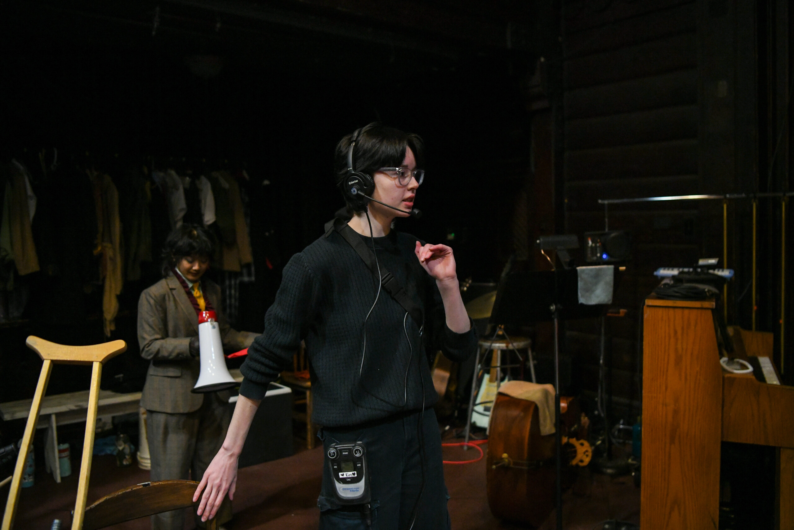 Student backstage at a theatre performance wearing all black and a headset.