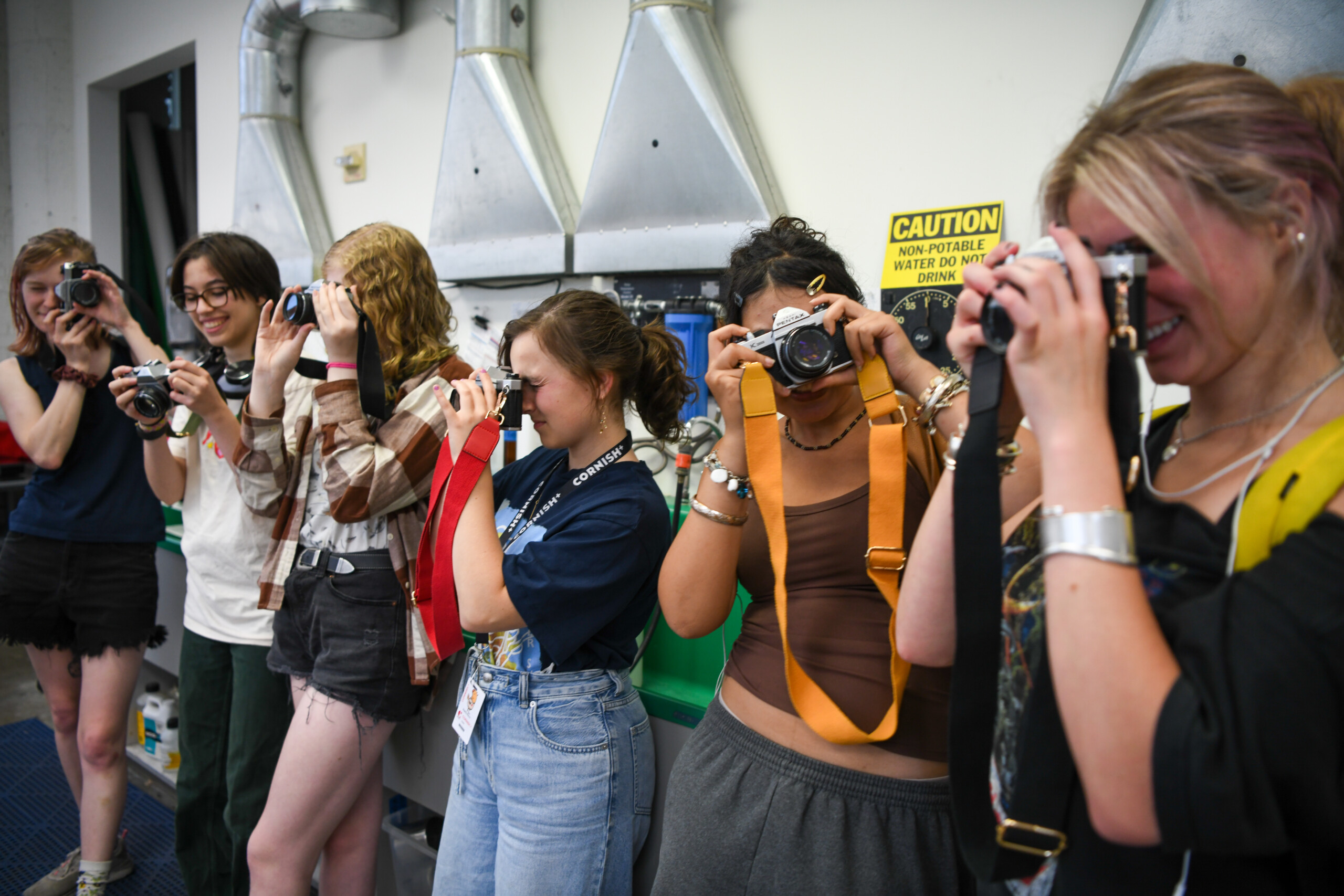 group of students holding various types of cameras pointed in different directions.